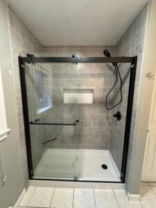 A modern walk-in shower with a low-flow showerhead, recycled glass tiles, and bamboo accents, showcasing an eco-friendly tub-to-shower conversion in a bright, clean bathroom.